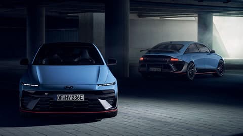 Два Hyundai IONIQ 6 N електрически спортни седана в слабо осветен паркинг, изглед отпред и отзад.