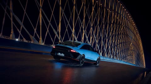Hyundai IONIQ 6 N пресича мост през нощта, заобиколен от осветени архитектурни елементи.