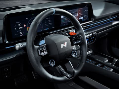 Детайлен изглед към волана на Hyundai IONIQ 6 N с бутони и дигитален инструментален клъстер на заден план.