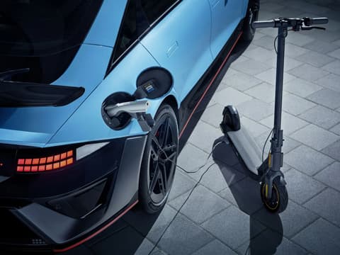 IONIQ 6 N зарежда електрически скутер чрез кабел на външна павирана площадка.