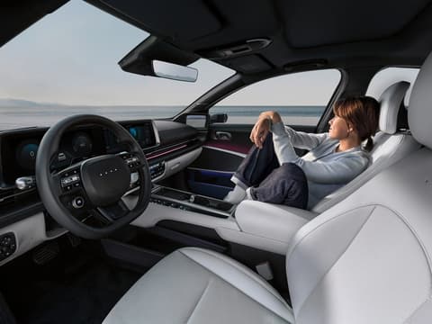 Жена, която се отпуска на пътническата седалка отпред в Hyundai IONIQ 6.