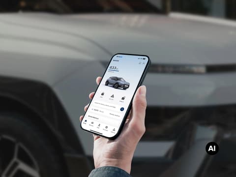 Ръка държи мобилен телефон в близък план, на фон Hyundai BAYON N Line.