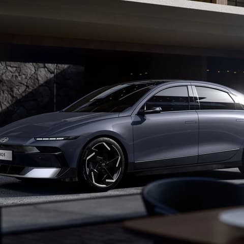 Hyundai IONIQ 6 електрически седан, паркиран пред модерна сграда.
