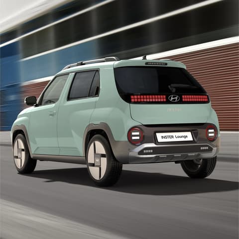 Hyundai INSTER Lounge в Glow Mint, показан отзад, движейки се по градска улица.