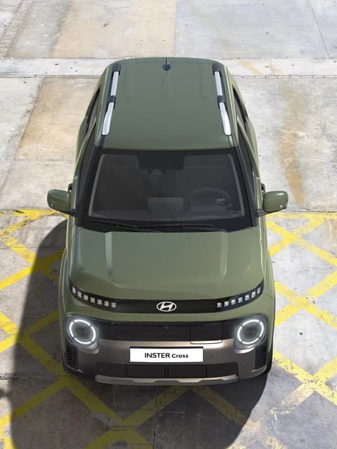 Заден изглед на Hyundai INSTER Cross, паркиран на хълм.