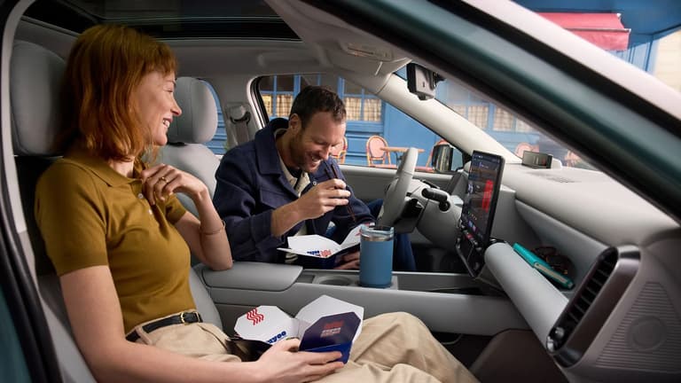 Мъж и жена се хранят с храна за вкъщи на предните седалки на Hyundai IONIQ 3.