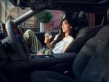 Изглед към интериора на Hyundai IONIQ 3 с човек на предната пасажерска седалка, показваща централната конзола и поставки за чаши.