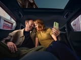 Интериор на Hyundai IONIQ 3 с черни седалки; двама души релаксират на задните седалки.