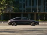 Hyundai IONIQ 6 електрически седан, сниман от нивото на улицата, паркиран с модерна сграда на заден план.