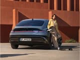Жена, опряна на IONIQ 6, зарежда електрически скейтборд, включен във външния заряден порт.
