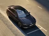HYUNDAI IONIQ 6, заснет отгоре в движение по слънчев път, подчертаващ изчистените форми и аеродинамичен стил.