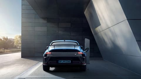 Заден изглед на Hyundai IONIQ 6 N, паркиран до модерна сграда с отворена шофьорска врата.