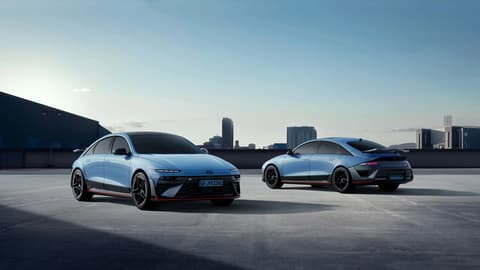 Два автомобила Hyundai IONIQ 6N паркирани на покрив с градски силует на заден план.