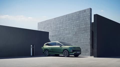 Hyundai IONIQ 9 електрически SUV, включен в зарядно устройство пред къща.