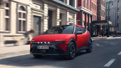 Red Hyundai IONIQ 3 driving in the urban street.