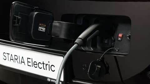Близък план на порта за зареждане на STARIA Electric с включен кабел за електрическо зареждане.