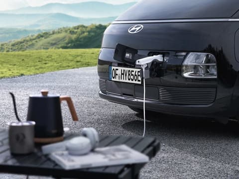 Преден порт за зареждане на Hyundai STARIA Electric, захранващ външно устройство чрез функцията Vehicle-to-Load (V2L).