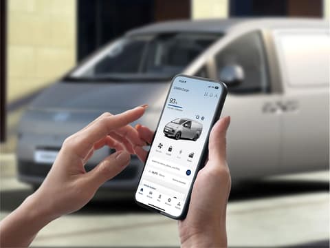 Приложението myHyundai на смартфон пред Hyundai STARIA Cargo.