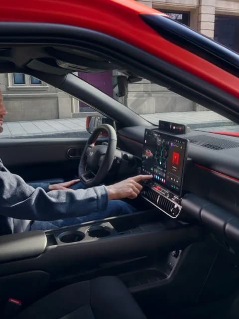 Черен интериор на Hyundai IONIQ 3 с централен екран; човек седи отпред.