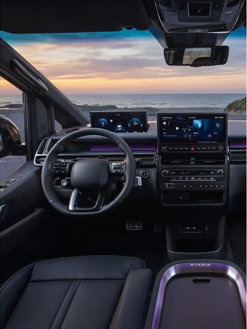 Цялостен изглед на интериора на Hyundai STARIA Electric, показващ областта на водача и пътника при залез.