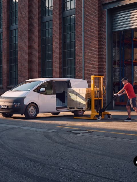 Товарене на палетизирани кашони в Hyundai STARIA Cargo пред склад.