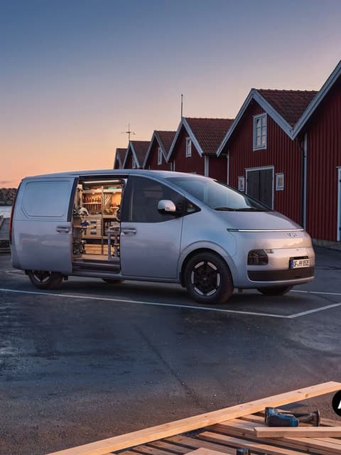 Hyundai STARIA Cargo, паркиран край водата, с отворена странична врата и вградени рафтове.