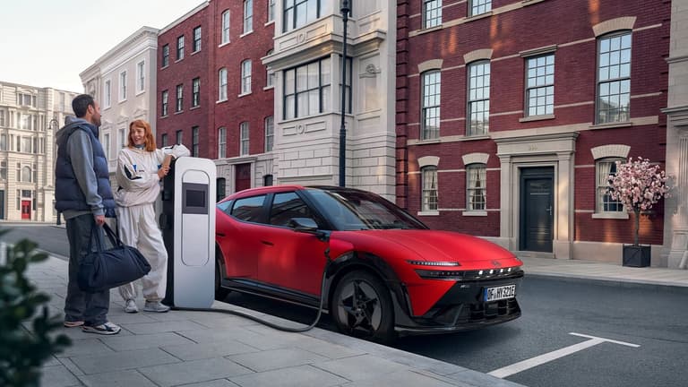 Hyundai IONIQ 3 charging on a city street with two people standing nearby.