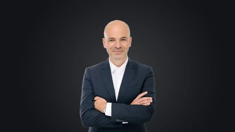 Манфред Харер, ръководител на Genesis и Performance Development Tech Unit, заснет със скръстени ръце на тъмен фон.