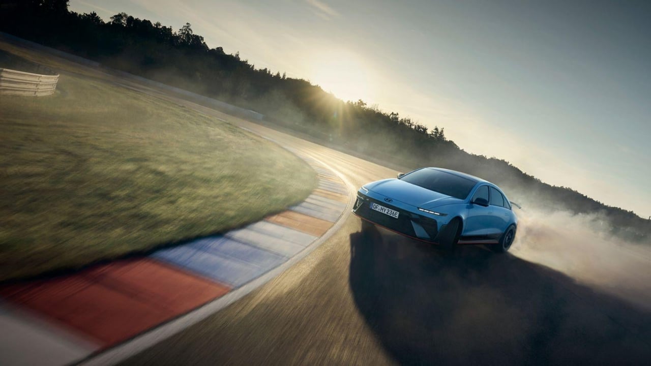 The Hyundai IONIQ 6 N drifts around a curve, capturing the excitement of high-speed driving at sunrise.