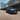 A blue Hyundai TUCSON driving down a long, empty street.
