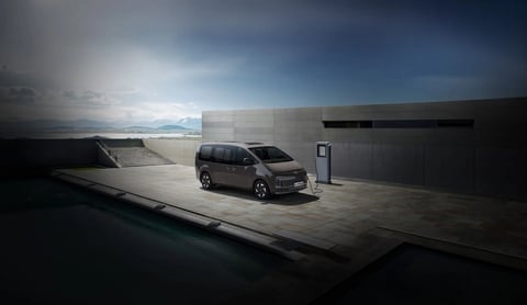 Hyundai STARIA Electric, свързан към EV зарядно на открито, подчертава удобния достъп до зареждане.