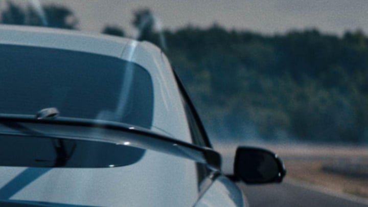 Rear view of a Hyundai IONIQ 6 N on a track, showcasing dynamic aerodynamics with smoke trailing behind.