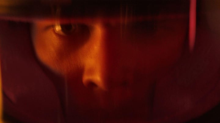 A close-up of a person's face wearing a reflective visor, revealing intense focus and determination.